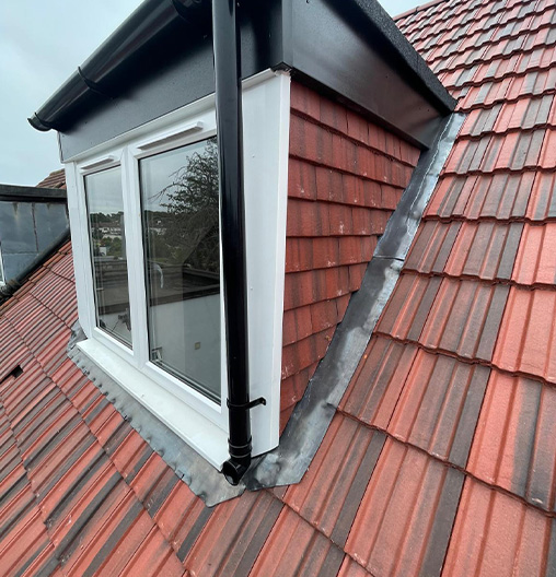 Newly installed dormer window with red roof tiles and metal flashing.