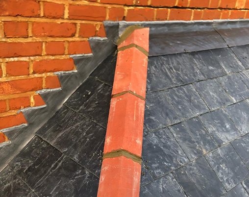 Slate roofing with a brick wall and ridge detail.