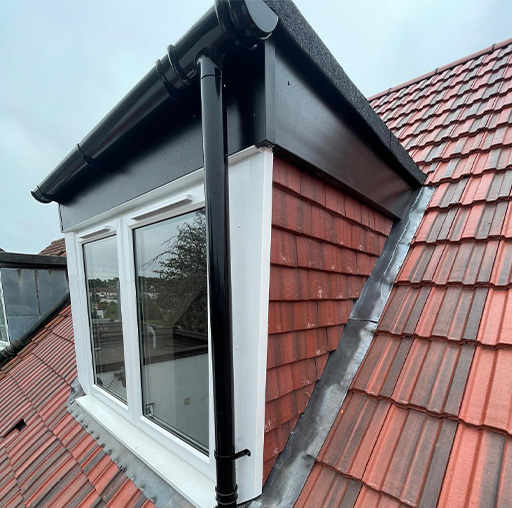 Roofline installation featuring a pitched roof with tiles and new windows.
