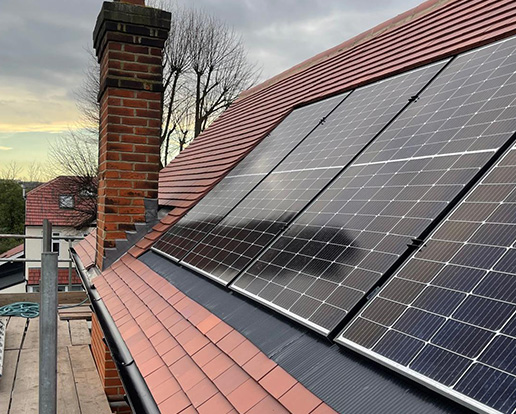 Roof with solar panels installed next to a chimney, showing roofing work completed by JC Roofing and Lofts Ltd.