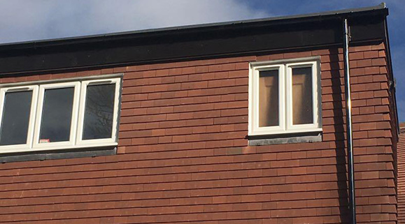Newly installed windows on a brown tiled exterior in residential property.